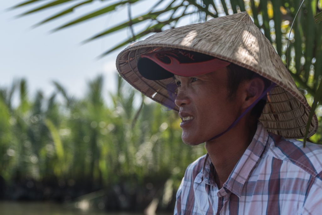 Vietnamese man with traditional hat in coconut forest